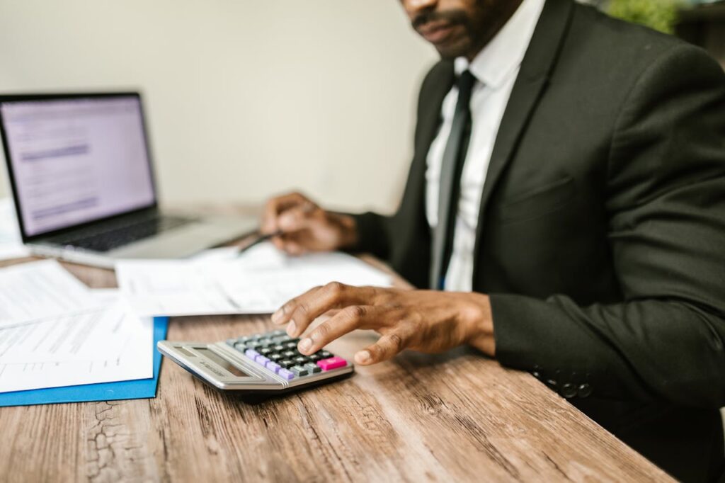 A man is sitting at a desk, calculating the average monthly deposit amount for a Tennessee bank statement loan. 