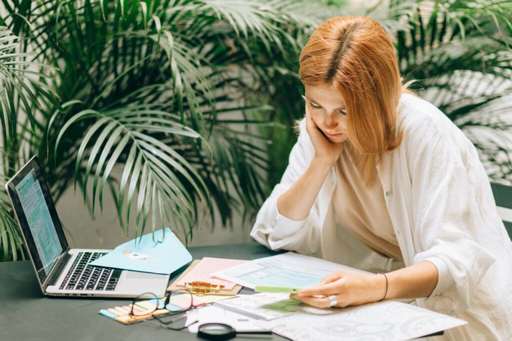 A woman sitting at a table with her laptop and documents to see if she's eligible for construction loans.