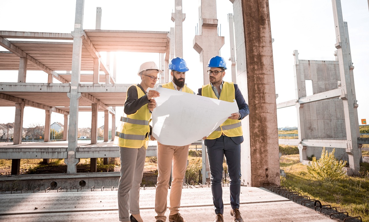 Three men are looking over building plans for a home being built with construction loans.