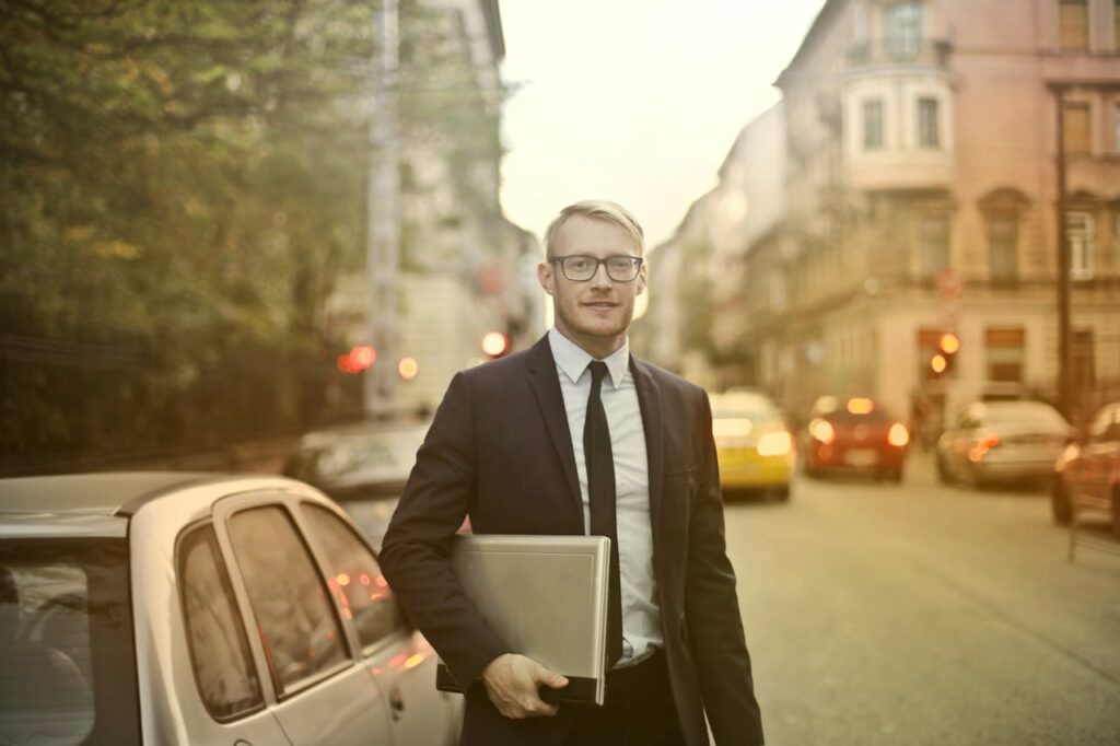 A real estate investor, who got a Massachusetts DSCR loan, is dressed in a suit and holding a laptop. 