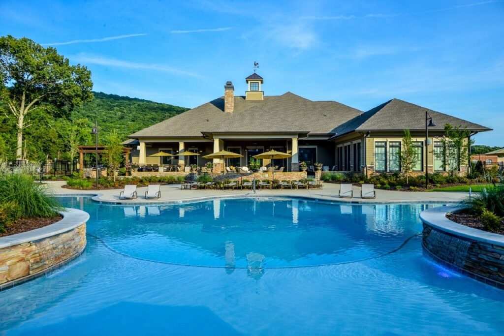 The view of a large home with a large pool from the backyard. 