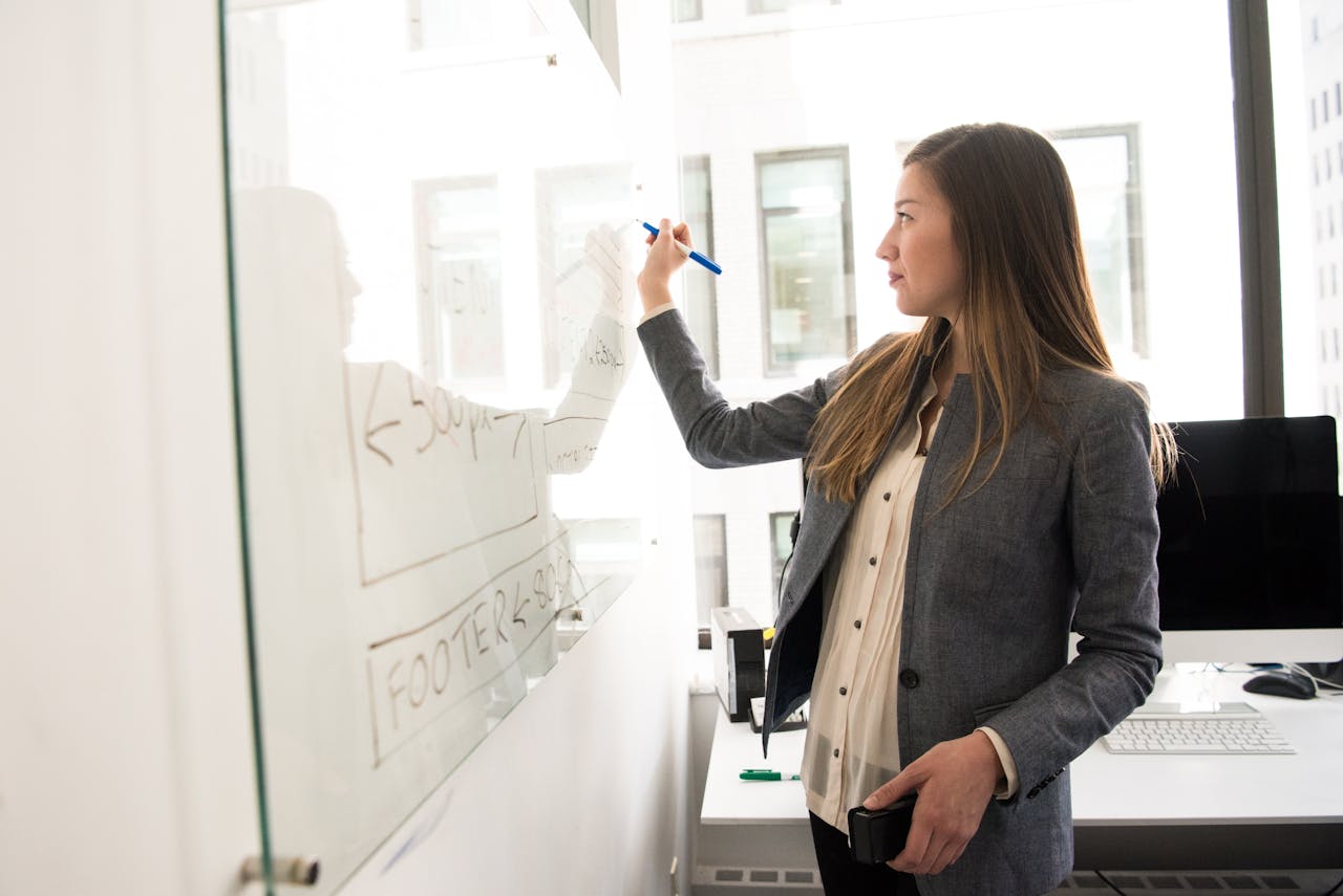 A woman is writing out the pros and cons of DSCR loans on a whiteboard to analyze.