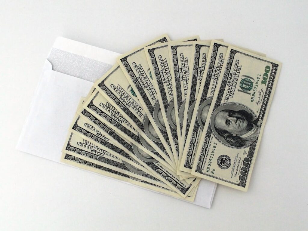 Several hundred dollar bills fanned out on top of an envelope that were received from cash-out refinance for investment properties. 