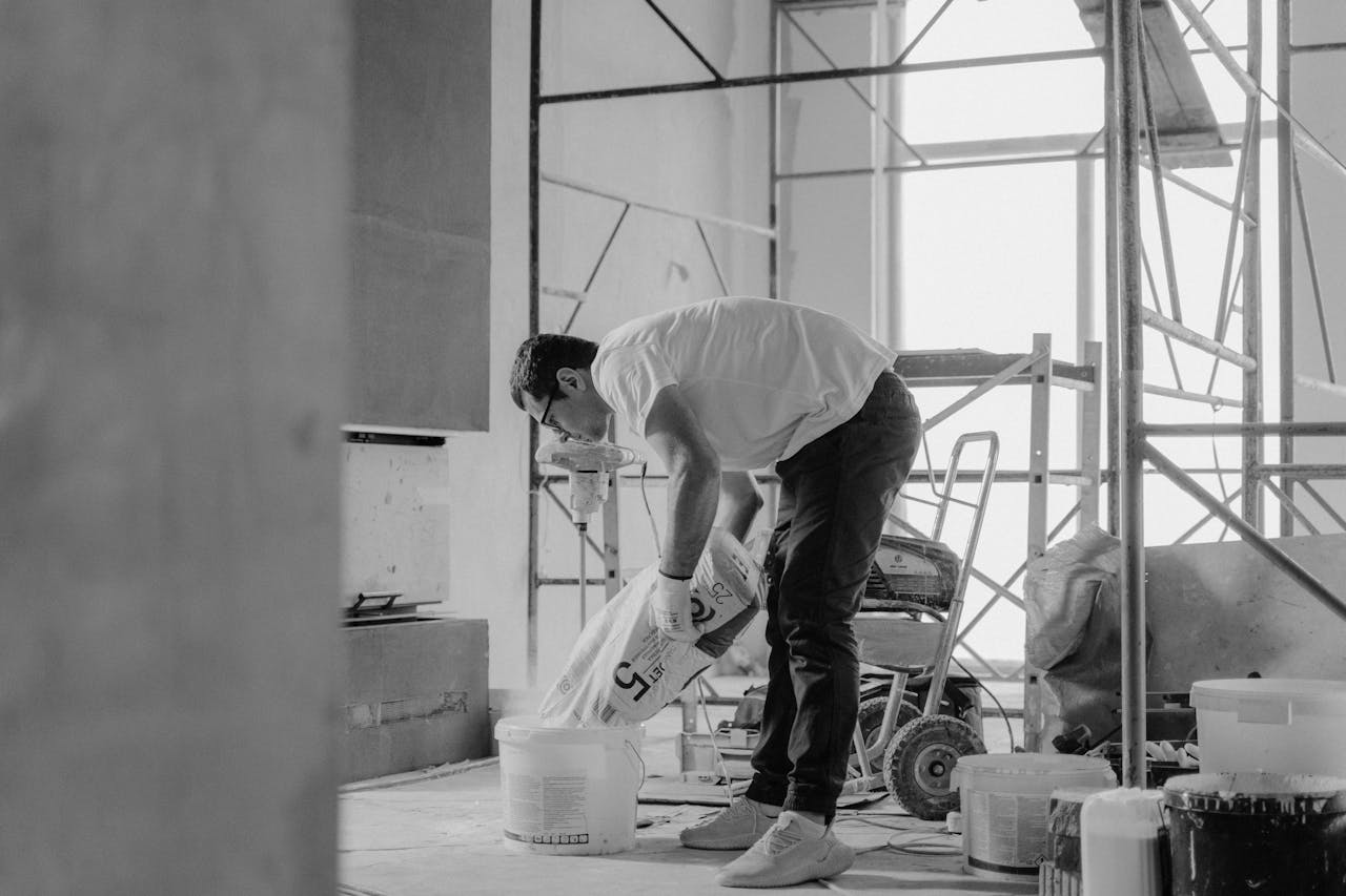 A man who purchased a fixer upper using DSCR loans for fix-and-flip projects is pouring building material into a bucket.