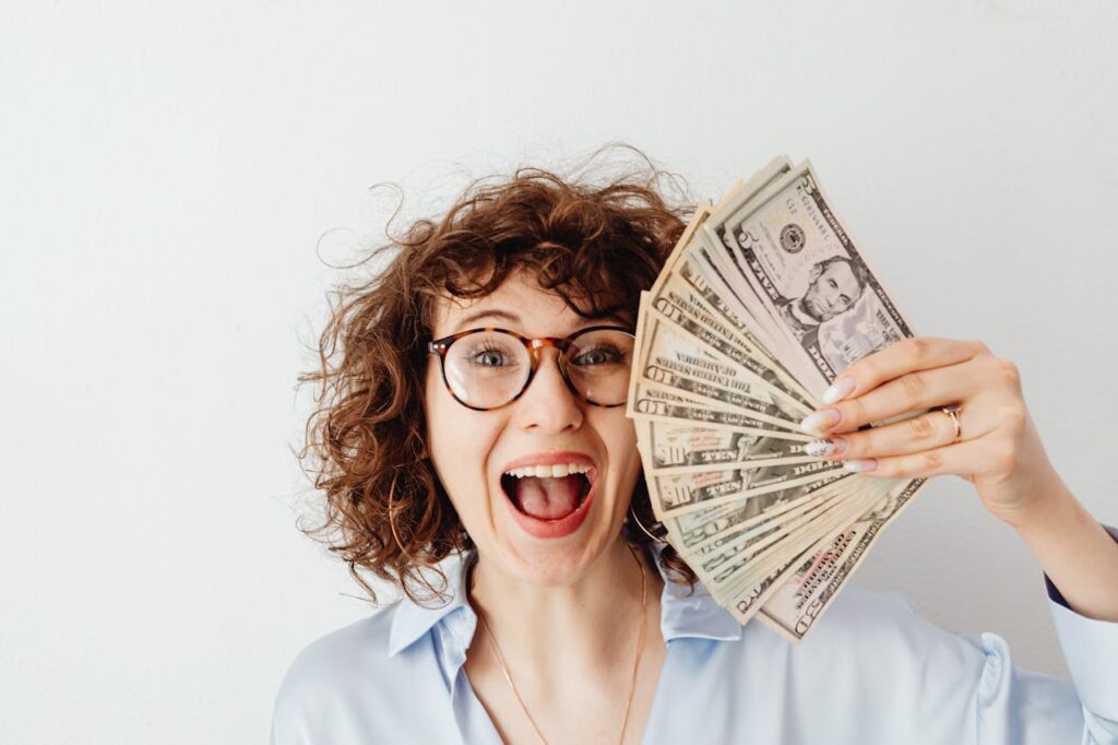 A woman is smiling while holding up the money she saved from refinancing during interest rate cuts. 