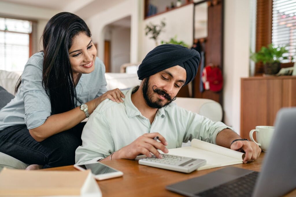 A South-Asian couple is smiling while evaluating their finances and making their long-term plan before interest rate cuts happen.