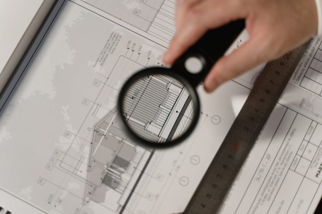 A magnifying glass looking over building plans for a new build that's financed by a construction loan Georgia. 