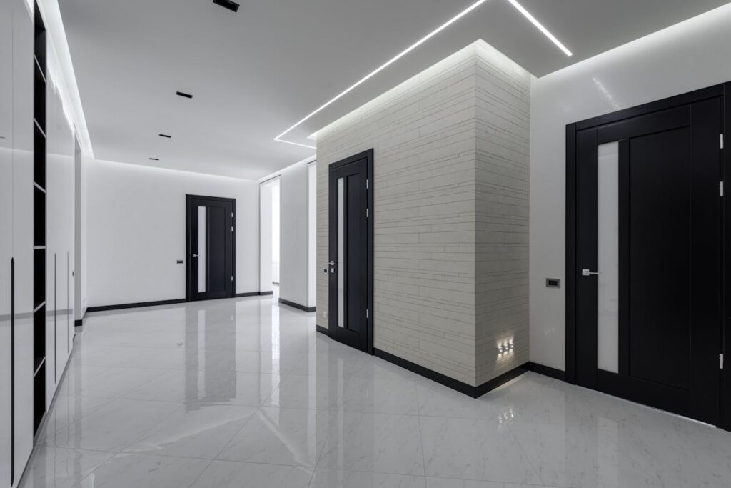 The hallway of a modern apartment building with doors to multiple occupied units. 