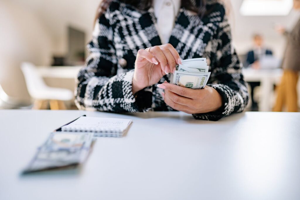 A woman is counting out $100 bank notes to make sure she has a financial cushion before considering any real estate investment loans. 