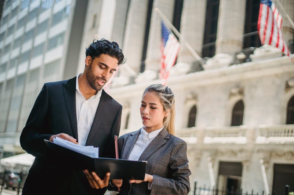 Two non-U.S. citizen real estate investors are reviewing papers for their foreign national loans California outside a bank building. 