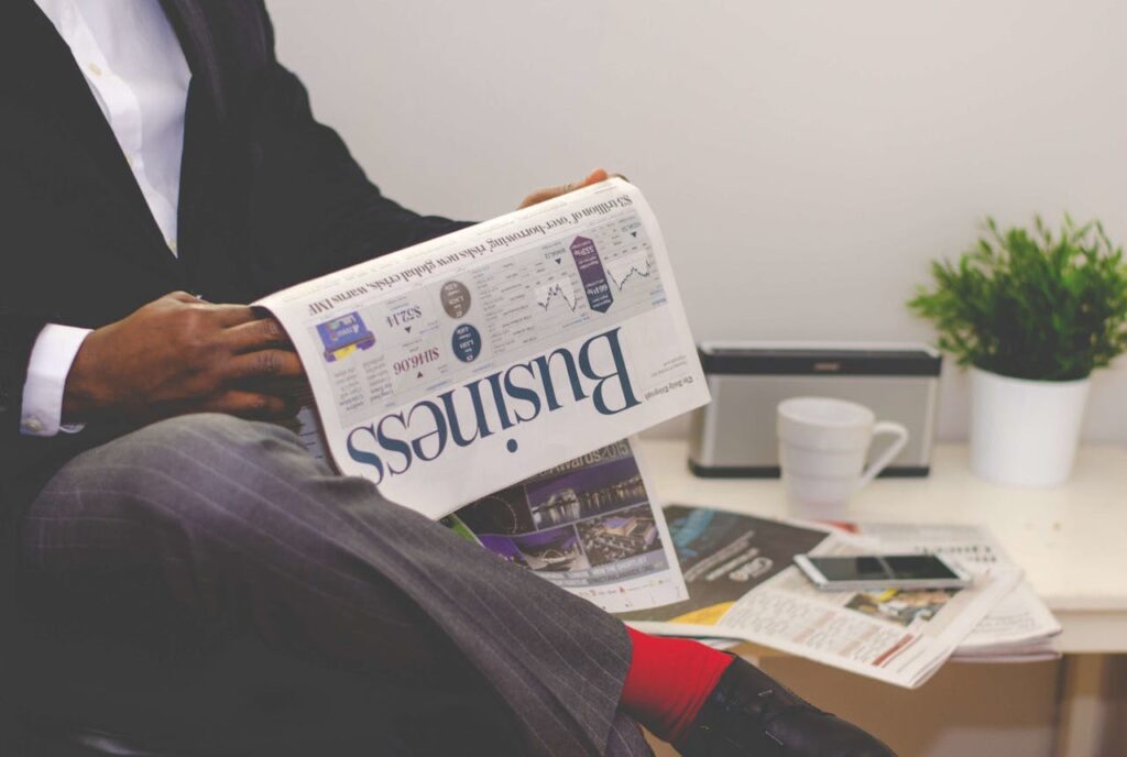 A real estate investor is reading the business section of a newspaper for news on the Fed rate cuts. 