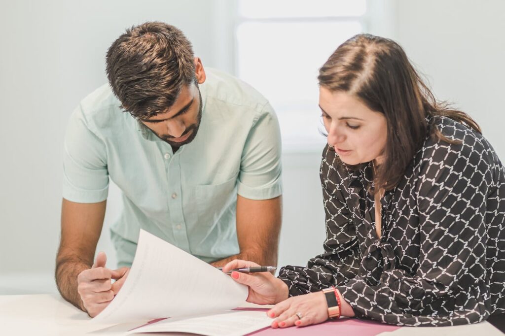 A couple is looking through and signing closing documents together to ensure they know when their first mortgage payment will be. 