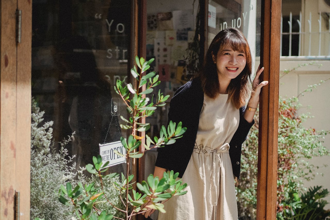 A woman is smiling outside her storefront, knowing how to prove income when self employed.