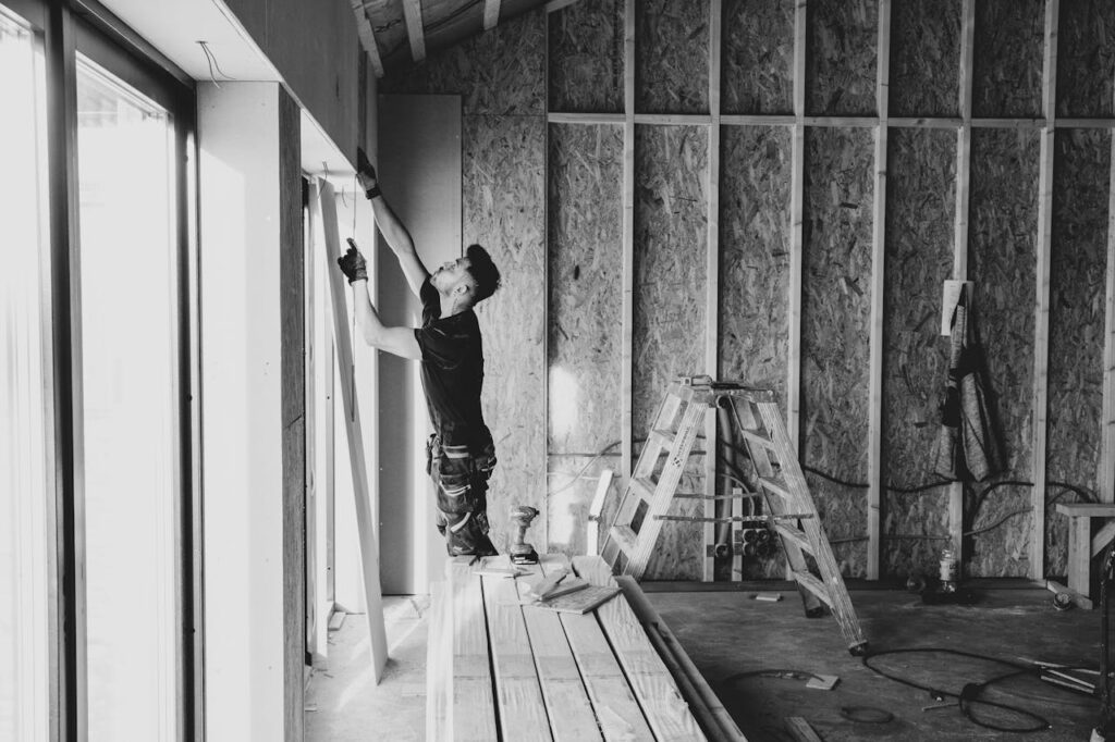 A builder measuring a sliding glass door in a house that's under construction and financed using an FHA construction loan. 