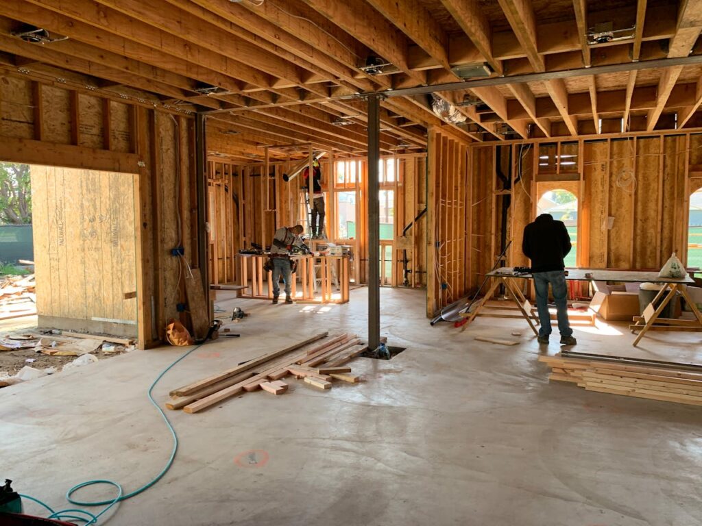 Three men sawing planks of wood and putting together the frame of a new home financed with an FHA construction loan. 