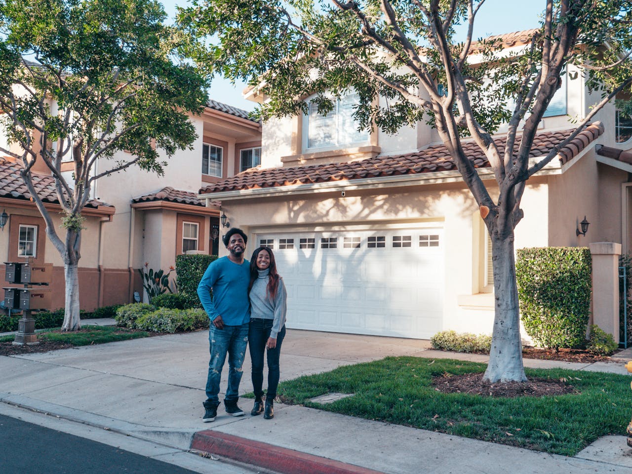 A couple standing in front of a single-family colonial home, which was purchased with an FHA loan application.