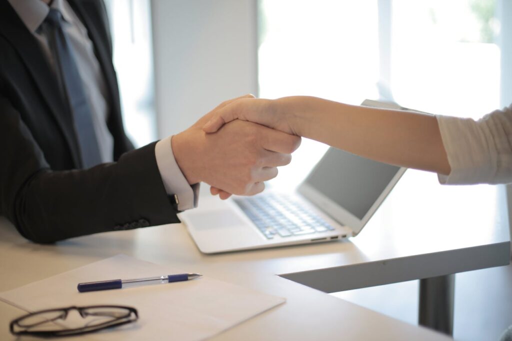 A lender shaking hands with a new homeowner after closing an asset based finance deal. 