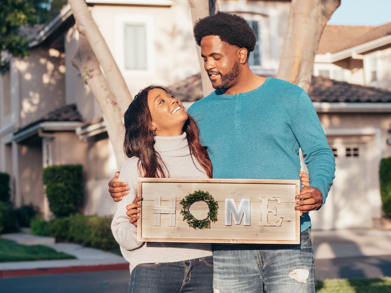 A couple who has learned how to get a loan without a job is standing in front of their new home together.