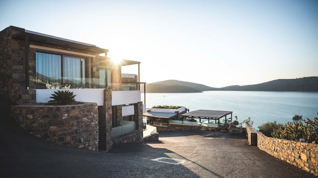 A luxury property investment sitting up on a hill, facing a beautiful body of water. 